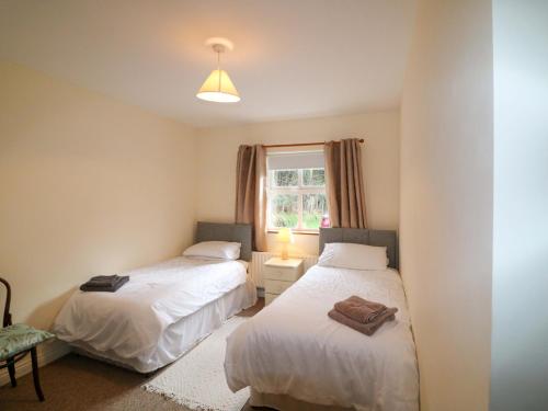 two beds in a small room with a window at Lugdine Lodge in Glengarriff