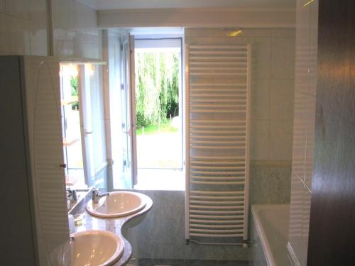 a bathroom with two sinks and a tub and a window at Chez clÉmentine in Antheny