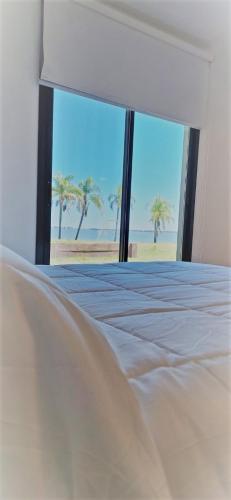 a bedroom with a bed with a view of the beach at GyC Laguna Resort in Chascomús