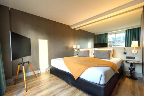 a bedroom with a bed and a flat screen tv at Hôbou - ex Hotel Acanthe in Boulogne-Billancourt