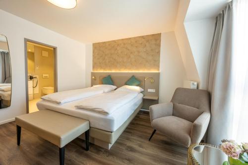 ein Hotelzimmer mit zwei Betten und einem Stuhl in der Unterkunft Hotel Plaza in Duisburg