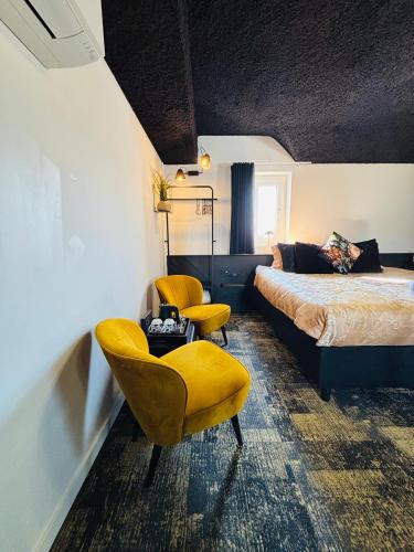 a bedroom with a bed and two yellow chairs at Bed & Breakfast Maison Noire Westende-bad incl parking & ontbijt in Middelkerke