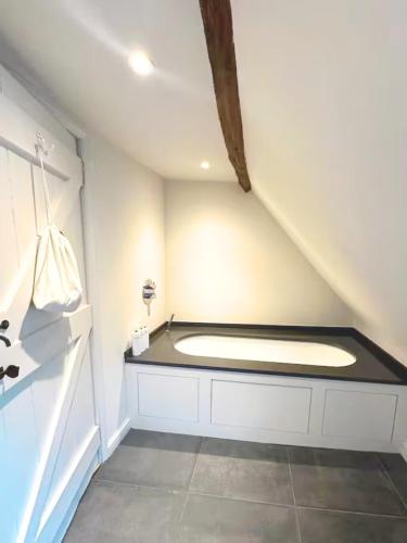 a bathroom with a tub in the corner of a room at West Pallant Georgian Townhouse in City Centre with Courtyards, BBQ & Log Burners - Dogs Welcome! Chichester Holiday Properties in Chichester