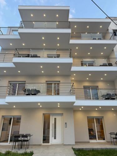 a facade of a building with tables and chairs at Villa Maria Apartments by BookVillaEU in Nea Kallikrateia