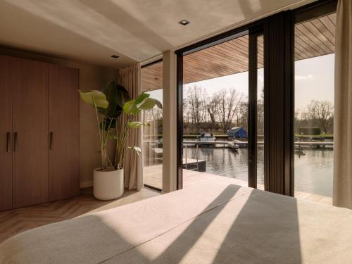 a bedroom with a large window with a view of the water at Haven Lake Village in Kortenhoef