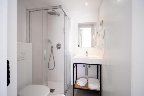 a white bathroom with a shower and a sink at Blanca by Uephotels in Can Picafort