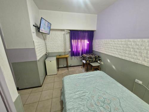 a room with a bed and a table and a window at Casona Sol in Mar del Plata