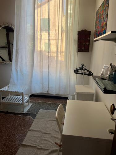 an office with a white curtain and a table and a window at Casa sulla spiaggia in Genoa