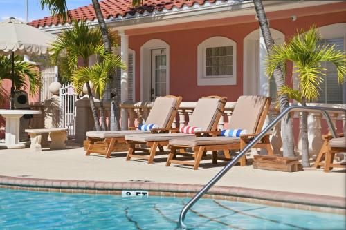 a pool with chaise lounge chairs next to a house at Blind Pass Resort Motel in St. Pete Beach