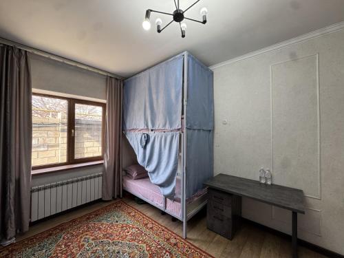 a room with a bed and a table and a window at Meridian Hostel in Almaty