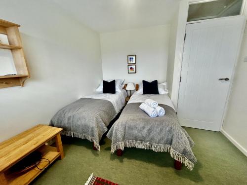 two twin beds in a room with a table at 16 Manesty View in Keswick
