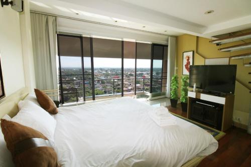 a bedroom with a white bed and a large window at Penthouse Galare Thong Tower - Stunning Views - Near Pool & Tennis in Chiang Mai