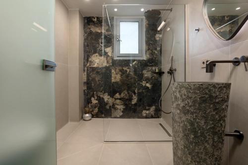 a bathroom with a shower with a glass door at Astarte Villas - Istar Villa with Tennis Court in Makhairádhon