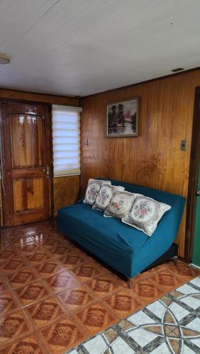 a blue bed in a room with a wooden wall at Cabaña La Petita in Cherquenco