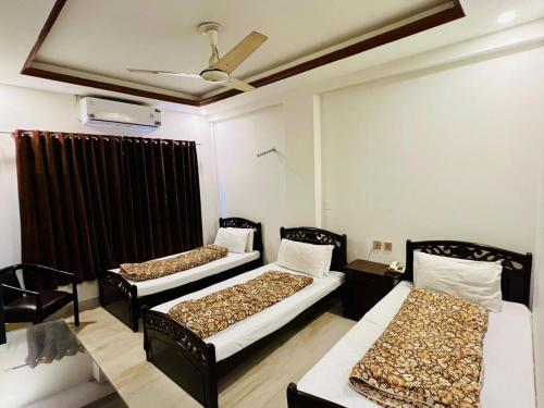 a room with three beds and a ceiling fan at Citymax Hotel in Rawalpindi
