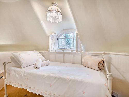 een slaapkamer met een wit bed en een kroonluchter bij 2 Bed in Wareham oc-79305 in East Stoke