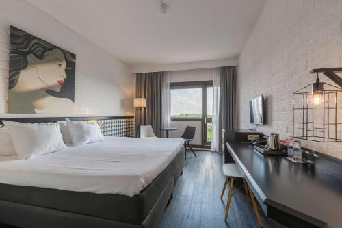 a hotel room with a bed and a desk at Leonardo Hotel Lelystad City Center in Lelystad
