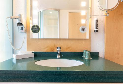 une salle de bains avec un lavabo et un miroir dans l'établissement B&B HOTEL Lully 3 Lakes, à Estavayer-le-Lac
