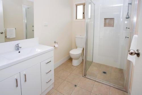 a white bathroom with a shower and a toilet at Albury Gardens Tourist Park in Lavington