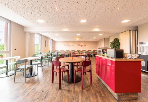 un restaurant avec des tables, des chaises et un comptoir dans l'établissement B&B HOTEL Lully 3 Lakes, à Estavayer-le-Lac