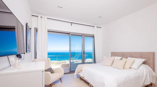 a white bedroom with a bed and a large window at Borderline in Al Matlīn