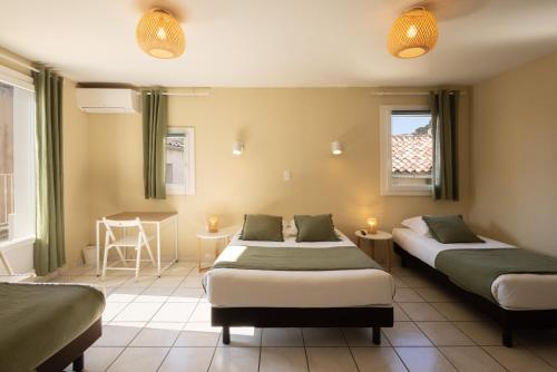 a room with two beds and a table and a table at L'Aptois Hôtel - Centre Ville - Local Vélos in Apt