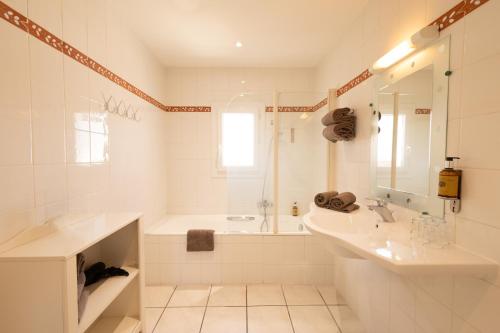 a white bathroom with a tub and a sink at L'Aptois Hôtel - Centre Ville - Local Vélos in Apt