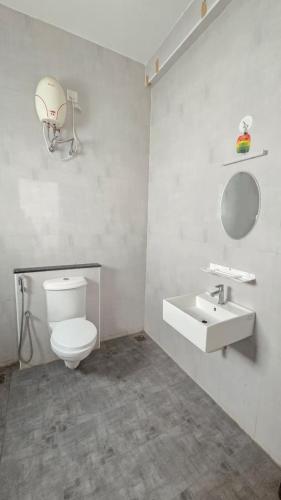 a bathroom with a white toilet and a sink at Noble Grand Villa in Mahabalipuram