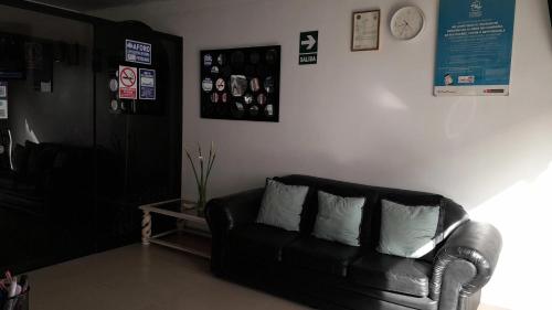 a living room with a black leather couch and a clock at Hostal Aurora a 3 cuadras de la Plaza de Armas in Cajamarca