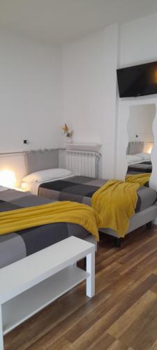 two beds in a room with a yellow blanket at Cristel malpensa room in Cardano al Campo