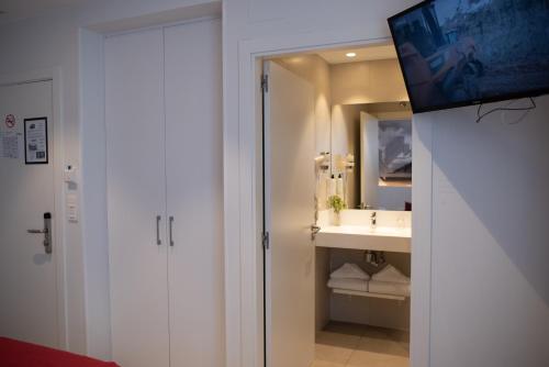 a bathroom with a sink and a tv on a wall at Pension y Apartamentos Txingurri Experience in Astigarraga