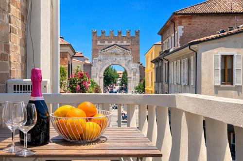 a bowl of oranges and a bottle of wine on a balcony at Suite Apartments - Corso51 in Rimini