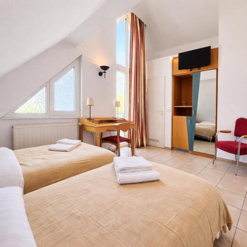 a hotel room with two beds and a desk at Airport Messe Villa Casa in Düsseldorf