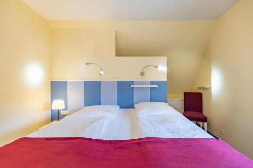 a bedroom with a large bed and a red chair at Dat lütte Huus - Wohnung 1 in Husum