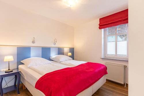 a bedroom with a large bed with a red blanket on it at Dat lütte Huus - Wohnung 2 in Husum