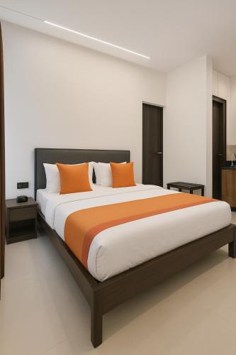 a bedroom with a large bed with orange pillows at Royal Guest inn HSR Layout in Bangalore