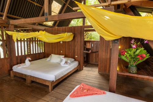 a bedroom with a bed with a hammock and flowers at La Kuka Hotel - Nuquí in Nuquí