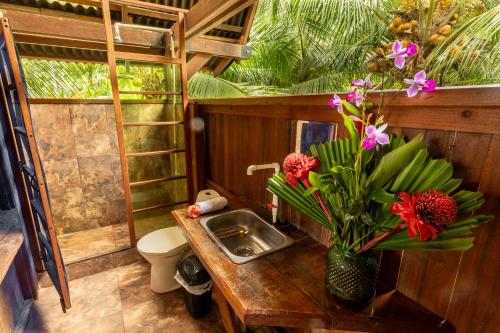 a bathroom with a sink and a vase of flowers at La Kuka Hotel - Nuquí in Nuquí