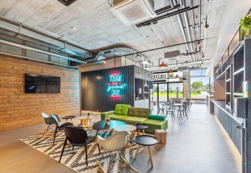 a lobby with a green couch and tables and chairs at B&B HOTEL Oftringen in Oftringen