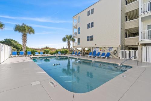 a swimming pool with chairs and a building at Lovely 2 bedroom condo with ocean view 304- 3rd Floor No Elevator in Myrtle Beach