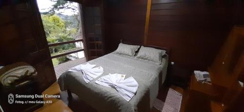 a bedroom with a bed with towels on it at Casa de Campo em Monte Verde in Camanducaia