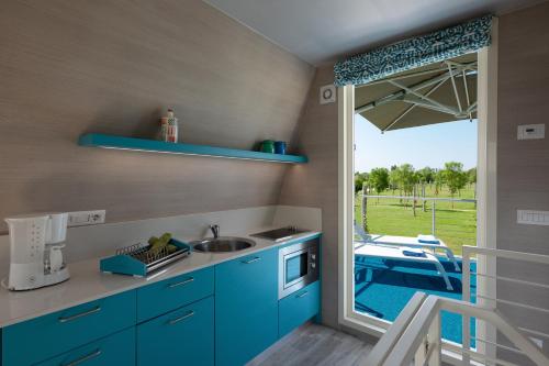a kitchen with blue cabinets and a view of a pool at Bungalow Marina Azzurra in Lignano Sabbiadoro