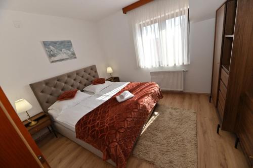 a bedroom with a large bed with a red comforter at Apartmani Lucija in Ludbreg