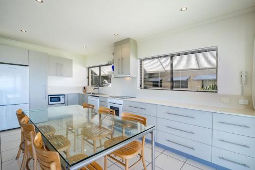 a kitchen with a glass table and some chairs at Sunseeker Holiday Apartments in Sunshine Beach
