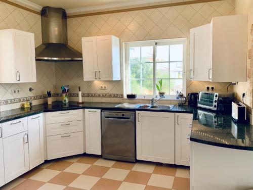 a kitchen with white cabinets and a sink and a microwave at Villa Hermano with views and private pool in Lagos