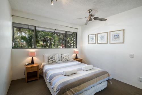 1 dormitorio con 1 cama con 2 lámparas y una ventana en Sunseeker Holiday Apartments, en Sunshine Beach