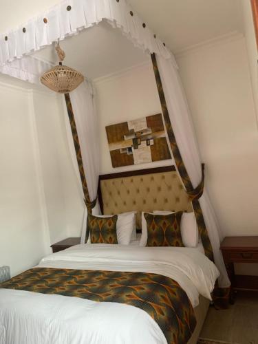 a bedroom with a canopy bed with white sheets and pillows at Kgcottage in Nairobi