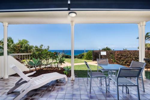 a patio with a table and chairs and the ocean at Sunseeker Holiday Apartments in Sunshine Beach