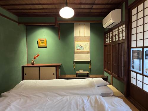 a bedroom with a white bed and green walls at 金沢町家ゲストハウスかるた in Kanazawa