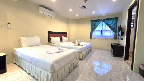 a hotel room with two beds and a television at Desa Phuket in Phuket